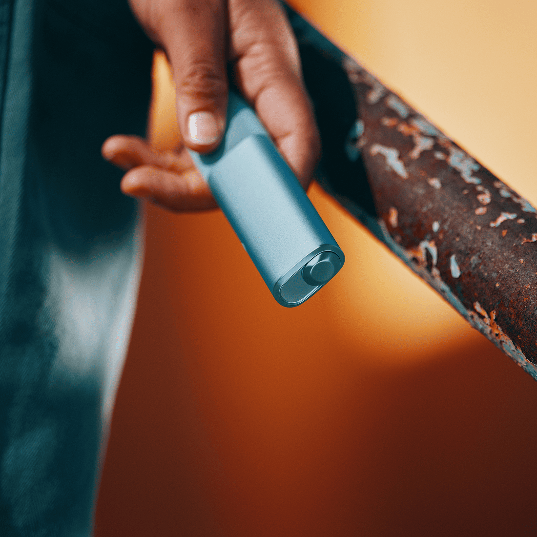 A person holding an IQOS ILUMA i ONE color Breeze Blue with their hand